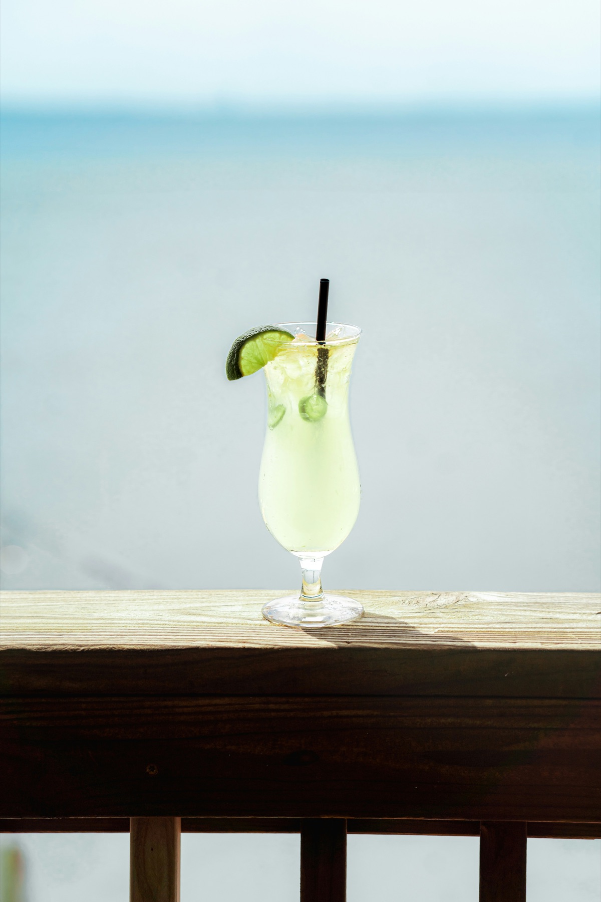 A cocktail served beside bright blue sea